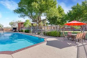 a swimming pool with a table and an umbrella at Best Western Mission Inn in Las Cruces