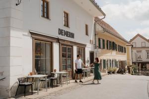 a man and a woman walking in front of a building at De Merin Boutique Hotel Straden in Straden
