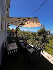 a balcony with tables and chairs and an umbrella at Mirayim Apart & Otel in Ardeşen