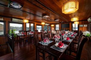 Un restaurante con mesas y sillas con flores rojas. en Garden Bay Classic cruise, en Ha Long