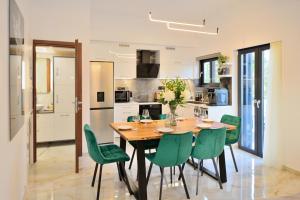 a kitchen and dining room with a wooden table and green chairs at Anatoli Apartment in Kissamos