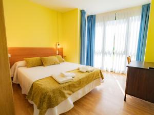 a yellow bedroom with a bed with towels on it at Pensión Palas in Palas de Rei
