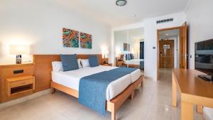 Un dormitorio con una cama, un escritorio y un televisor. en Ukino Palmeiras Village - 24h All Inclusive, en Armação de Pêra