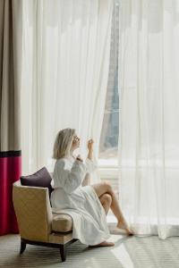 a woman sitting in a chair looking out of a window at Taj Dubai in Dubai