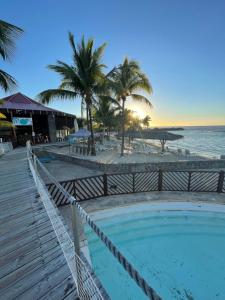 a swimming pool next to a beach with palm trees at Studio 25 m Manganao Joela 4 personnes avec machine a laver in Saint-François