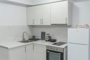 a kitchen with white cabinets and a sink and a refrigerator at Niki's Apartments in Faraí +9 photos