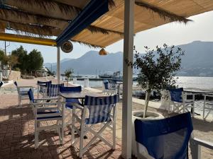 a table and chairs on a beach with a tree at Villa Telendos in Telendos