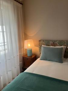 a bedroom with a bed with a lamp and a window at Fortaleza Faro in Valença