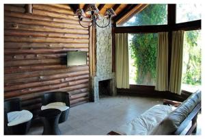 a living room with a log wall with a fireplace at Cabaña Gertrudis in Sierra de los Padres