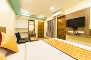 a hotel room with a bed and a flat screen tv at SAU Residency in Kanchipuram