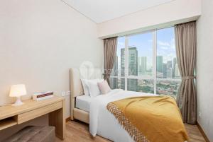 a bedroom with a bed and a desk and a window at Lanea by Kozystay - Setiabudi in Jakarta