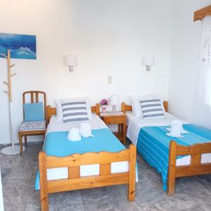 a room with two beds and a chair at Massouri Rooms in Masouri