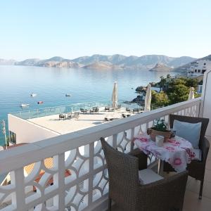 a balcony with a table with a view of the water at Massouri Rooms in Masouri