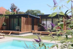 a house with a swimming pool in a garden at Hôtel Le Grain de Sable in Arès