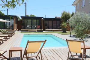 a swimming pool with two chairs and a table and a table and chairs at Hôtel Le Grain de Sable in Arès