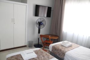 a hotel room with two beds and a fan at One03 Guest house in Harare