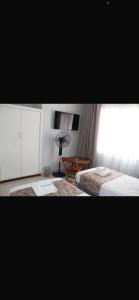 a bedroom with a bed and a desk with a fan at One03 Guest house in Harare