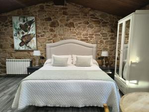 a bedroom with a large bed with a stone wall at A Casa Da Canle in Braño +61 photos