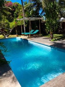 a blue swimming pool with a bench in a yard at Jardin D'éole - Boutique Hotel in Fortim