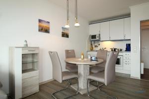 Una cocina y un comedor con mesa y sillas. en Urlaub mit spektakulärer Aussicht auf das Wattenmeer, en Cuxhaven