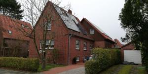 una casa de ladrillo rojo con garaje blanco en Ferienhaus Méhaux 11, en Cuxhaven