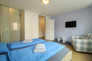 ein Schlafzimmer mit einem blauen Bett und einem Sofa in der Unterkunft Residenz Hohe Lith Wohnung 04 01 in Cuxhaven + 13 Fotos