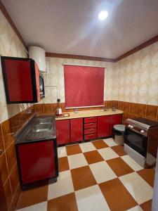 a kitchen with red cabinets and a checkered floor at واحة دار السلام للشقق المخدومة الجوف دومة الجندل in Dawmat al Jandal