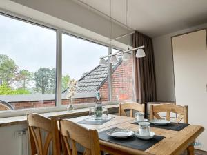 a dining room table with chairs and a large window at Refugium Storchenwiese Wohnung 2 in Cuxhaven +12 photos