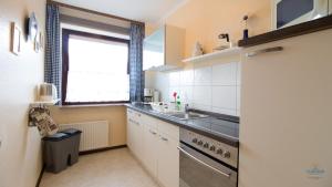 Una pequeña cocina con fregadero y ventana. en Haus Kerstin Duhnen Wohnung 8, en Cuxhaven