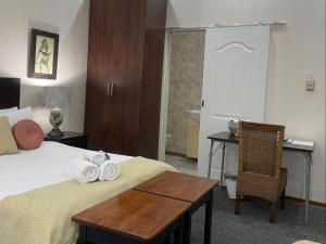 a bedroom with a bed with a desk and a chair at 12 On York Guesthouse in Bloemfontein +27 photos
