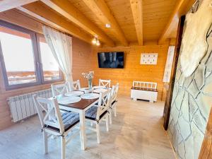 a dining room with a table and chairs and a tv at Domek Hulanka in Szczyrk
