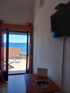 a living room with a table and a large window at Orchid in Selce