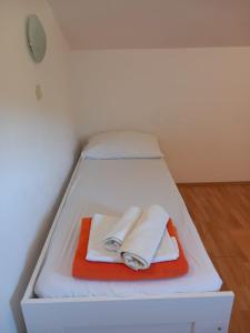 a small white bed with two towels on it at Orchid in Selce