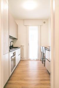 a kitchen with white cabinets and a wooden floor at Ca' Martha - A due passi dal centro con parcheggio privato - Aeroporto 2 chilometri in Treviso