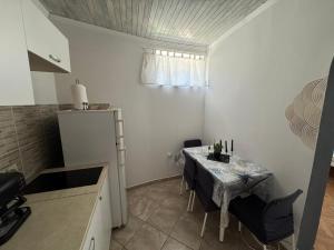 a small kitchen with a table with chairs and a window at Apartmani Luciano in Novalja