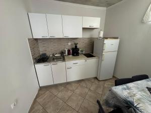 a kitchen with white cabinets and a sink and a refrigerator at Apartmani Luciano in Novalja