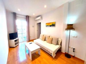 a living room with a white couch and a tv at Maravilla Apartment in Seville