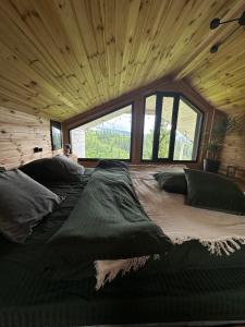 a large bed in a room with a large window at Карпатське Hygge котедж для двох з чаном-джакузі у горах in Slavske +160 photos
