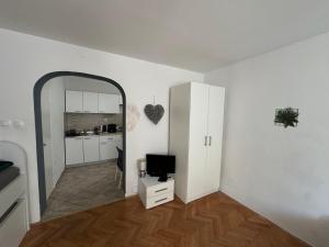 a white living room with a mirror and a television at Apartmani Luciano in Novalja