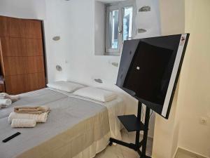 a bedroom with a large flat screen tv on a bed at Aristotelis Homes in Katapola