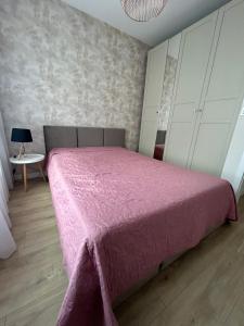 a bedroom with a pink bed with a pink blanket at Premium Apartament Koronowska 40m2 in Bydgoszcz