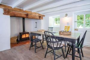 a dining room with a table and chairs and a wood stove at Briardene - 2 Bedroom Cottage - Oxwich in Oxwich