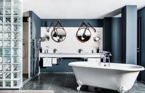 bagno con vasca bianca e pareti blu di Grand Ferdinand Vienna – Your Hotel In The City Center a Vienna