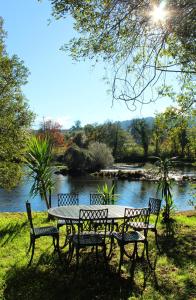 a picnic table and two chairs next to a lake at Casa do Rio - Eido do Pomar in Arcos de Valdevez