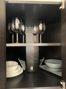 four wine glasses and plates on a shelf at Udine Station Apartment in Udine +20 photos