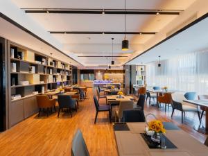 a restaurant with tables and chairs and a library at Echarm Hotel - Wuhan Jingkai Yongwang Sports Center in Wuhan
