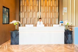 a man sitting at a counter in a room at Echarm Hotel - Wuhan Jingkai Yongwang Sports Center in Wuhan