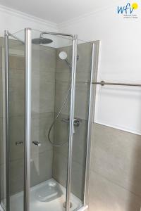 a shower with a glass door in a bathroom at Luv und Lee - Ferienwohnung Juister Stuv in Juist