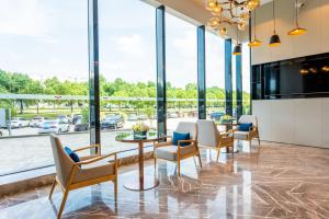 a lobby with tables and chairs and large windows at Echarm Hotel - Wuhan Jingkai Yongwang Sports Center in Wuhan