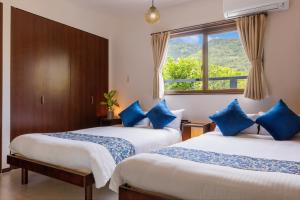 two beds with blue pillows in a room with a window at Anew villa on Tokashiki island, walk to the beach in Awaren
